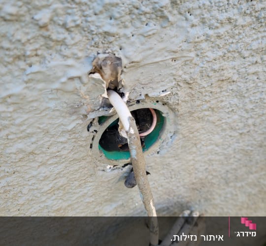 כבל חשמלי יוצא מקיר עם חור